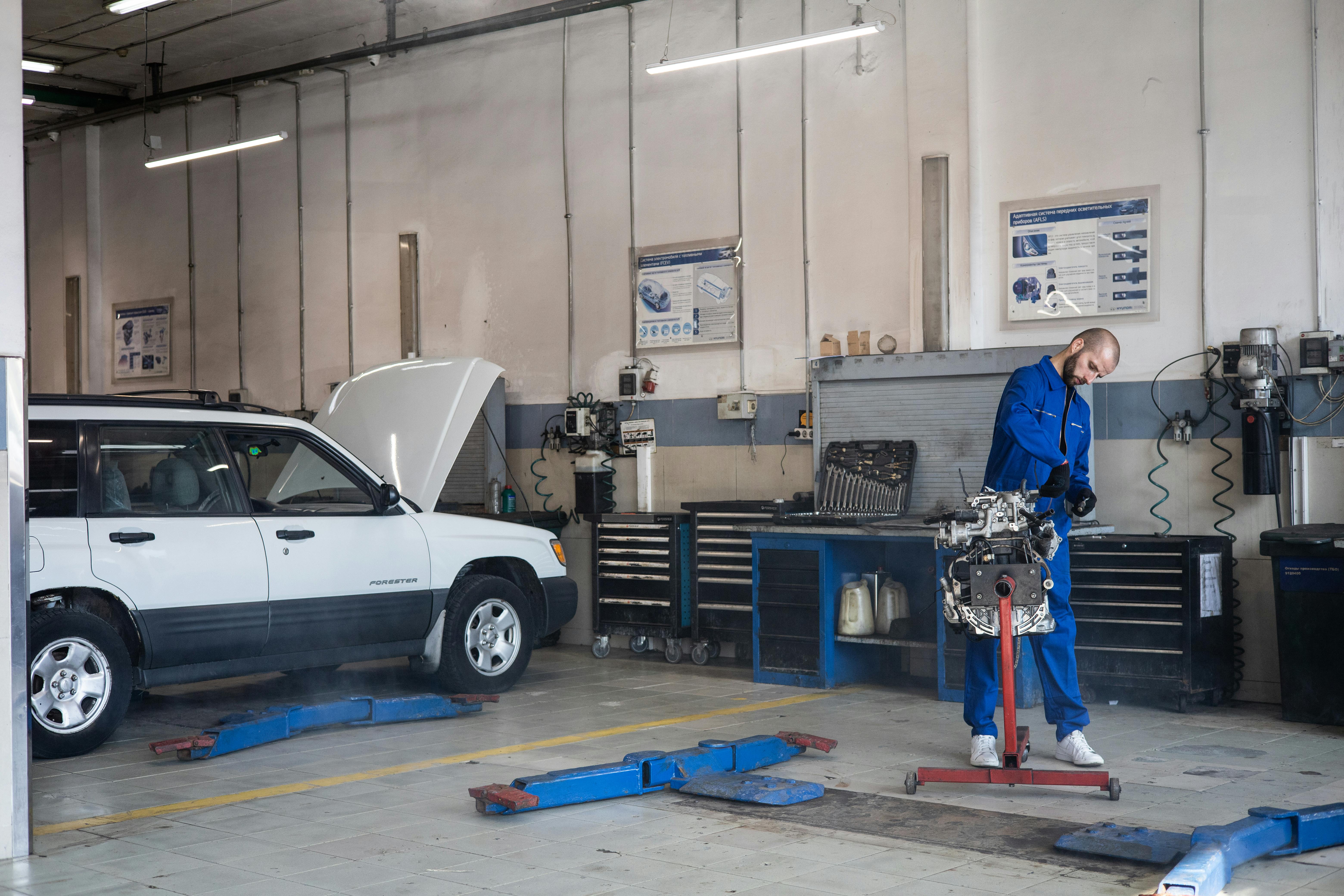 Auto electrician workshop bay with vehicle on lift and diagnostic equipment.